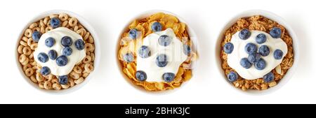 Drei Schüsseln mit verschiedenen Cerealien mit Joghurt und frischen Blaubeeren auf weißem Hintergrund isoliert, Draufsicht Stockfoto