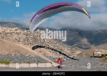 Gleitschirm mit Instruktor Pilot im Tandem Landung auf dem Boden vor den Bergen auf Teneriffa Stockfoto