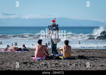 Ein Strandverkäufer mit Weihnachtsartikeln und Hut verkauft an Touristen in der Wintersonne auf Teneriffa Stockfoto