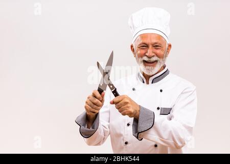 Bild von glücklichen Koch schärft Messer auf grauem Hintergrund. Stockfoto