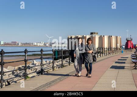 Zwei Frauen, die entlang der Promenade von New Brighton am Fluss Mersey, Wirral Peninsula, spazieren Stockfoto