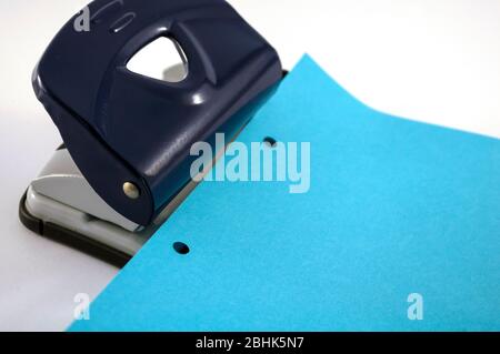 Büro: Punsch, blaues Papier mit Lochungen auf weißem Hintergrund mit Platz für Text Stockfoto