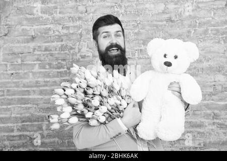 Warten auf Darling. Mann gut gepflegt Verschleiß tuxedo Bow Tie halten Blumen Tulpen Bouquet und großen Teddybären Spielzeug. Laden Sie dating. Romantisches Geschenk. Romantischen Mann. Macho fertig, romantisches Date. Stockfoto