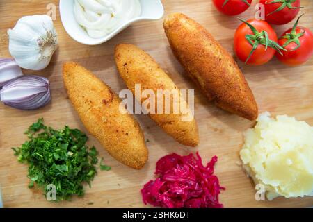 Ukrainische Tradition Essen auf einem Holzbrett. Rotkohl Sauerkraut in einer kleinen Schüssel . Kartoffelpüree . Mayonnaise, Knoblauch, Zwiebeln, Tomaten. Gehackt Stockfoto