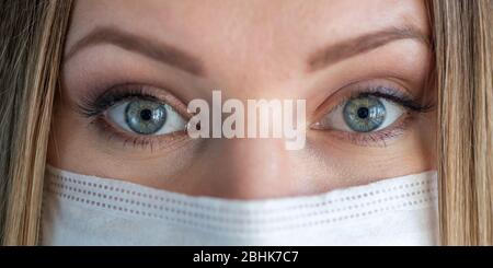 Nahaufnahme Auge des erwachsenen weiblichen Chirurgen Arzt mit Schutzmaske. Gesundheitswesen, medizinische Notfalldienste und Chirurgie Konzept Stockfoto