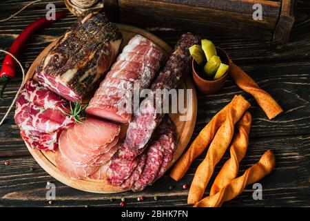 Fleischspezialitäten auf Holzhintergrund, getrocknete Wurst auf einem Schneidebrett Stockfoto