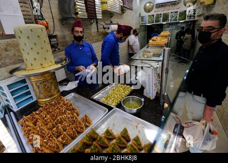 Beirut, Libanon. April 2020. Ein Mann kauft während des Ramadan inmitten der COVID-19-Pandemie in Beirut, Libanon, am 26. April 2020 Süßigkeiten. Die Zahl der COVID-19-Infektionen im Libanon stieg am Sonntag um drei Fälle auf 707 an, während die Zahl der Todesopfer unverändert bei 24 blieb, berichtete die Nationale Nachrichtenagentur. Kredit: Bilal Jawich/Xinhua/Alamy Live News Stockfoto