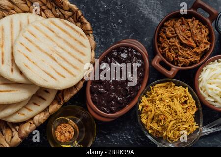 Blick von oben auf typisch lateinamerikanische Küche. Gruppe von arepas und verschiedene Arten von Zutaten, um sie zu füllen Stockfoto