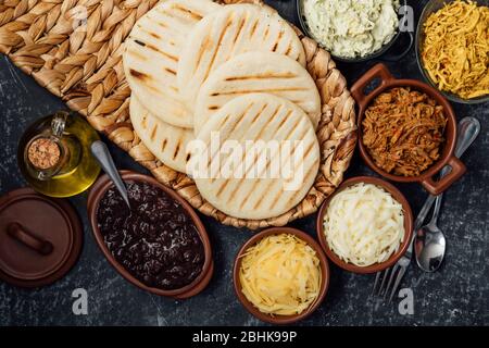 Blick von oben auf typisch lateinamerikanische Küche. Gruppe von arepas und verschiedene Arten von Zutaten, um sie zu füllen Stockfoto