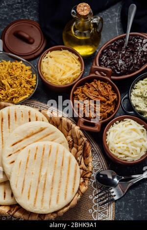Blick von oben auf typisch lateinamerikanische Küche. Gruppe von arepas und verschiedene Arten von Zutaten, um sie zu füllen Stockfoto