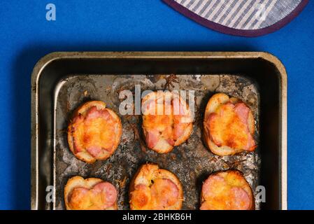 Kochen eine schnelle Mahlzeit. Gebackene Sandwiches mit Wurst und Käse in einem Backblech auf blauem Hintergrund Stockfoto