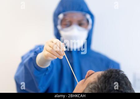 Abstrichtest durch NHS-Mitarbeiter an einem Patienten mit blauer voller PSA während der Covid19-Pandemie, um einen Coronavirus-Impfstoff zu finden Stockfoto