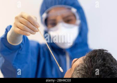 Abstrichtest durch NHS-Mitarbeiter an einem Patienten mit blauer voller PSA während der Covid19-Pandemie, um einen Coronavirus-Impfstoff zu finden Stockfoto