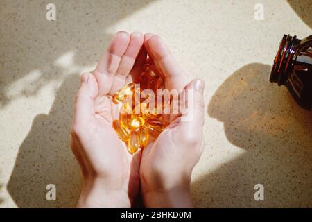 Handvoll Omega 3 Kapseln in der Hand bei Sonnenlicht. Stockfoto