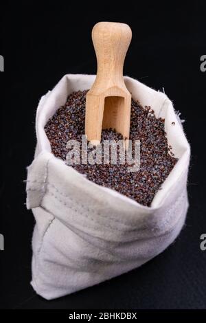 Leckere und saubere Mohn Samen in Stoffbeutel. Zutaten für köstliche Desserts und andere Gerichte auf dem Tisch. Dunkler Hintergrund. Stockfoto