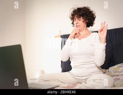 Frau, die Yoga-Meditation und Pranayama-Atmung praktiziert, blockiert ein Finger ein Nasenloch und die andere Hand ist in surya Mudra Position, Yoga Online-Lesso Stockfoto