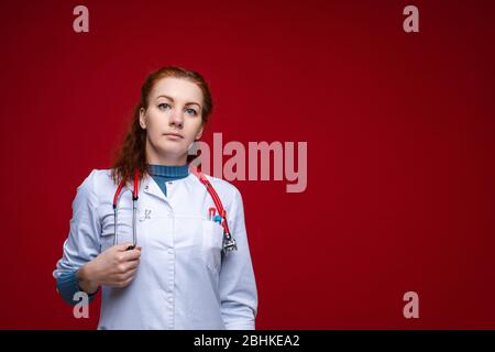 Schöne rothaarige Arzt im Labormantel mit Stethoskop. Stockfoto