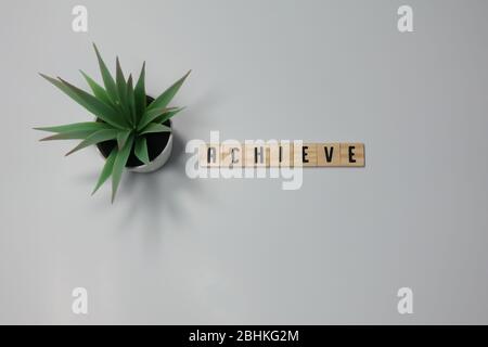 Das Wort Achieve ist in hölzernen Buchstabenfliesen auf weißem Hintergrund geschrieben. Konzept Geschäftserfolg, Gewinn und Ziele. Stockfoto