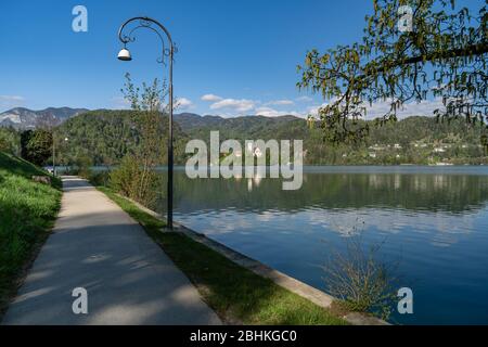 Restriktive Maßnahmen aufgrund des Coronavirus in Aktion. Gehweg mit einer geklebten Bank. Bled Insel mit einer Kirche im Hintergrund. Stockfoto