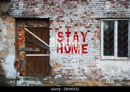 Bleiben Sie zu Hause Inschrift auf alten Ziegelwand.versiegelte Tür und versperrte Fenster. Selbstisolierung zu Hause von einem Coronovirus-Konzept Stockfoto