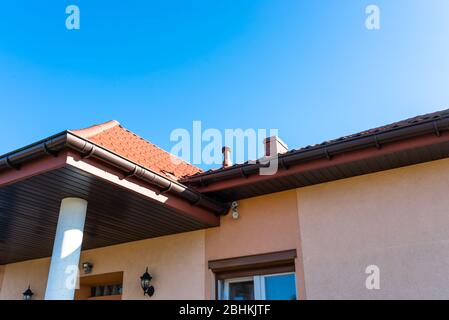 Höhe des Gebäudes in Lachsfarbe mit einer Betonsäule, Holzsoffit und Überwachungskameras an der Wand. Stockfoto