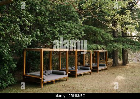 Braune Strandzelte aus Holz stehen im Wald. Graue Strandsofas Stockfoto