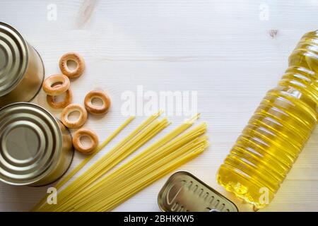 Nahrungsmittelversorgung, Krise Nahrungsmittelvorrat für Quarantäne Isolationsperiode auf einem hellen hölzernen Hintergrund. Pasta, Öl, Konserven, Bagels. Stockfoto