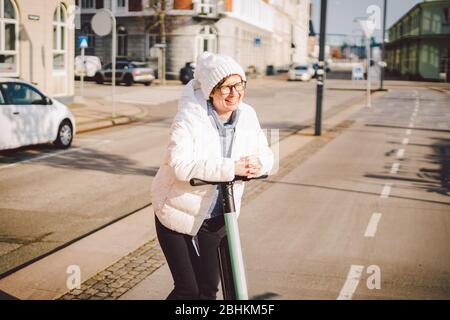 Tourist Frau mieten Elektroroller in der dänischen Hauptstadt Kopenhagen. Weibliche Lenksäulenknopf mit elektrischem Kick Scooter Griff auf der Straße in Stockfoto