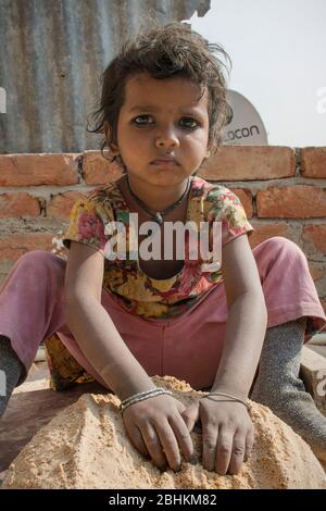 Armes Mädchen auf dem Land spielt mit Sand in indien Stockfoto