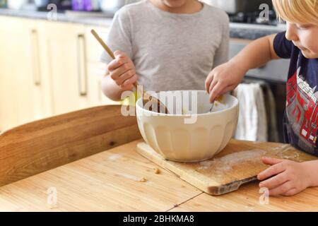 Kinder rühren in der Küche zuhause beim Backen von Plätzchen eine Rührschüssel um Stockfoto