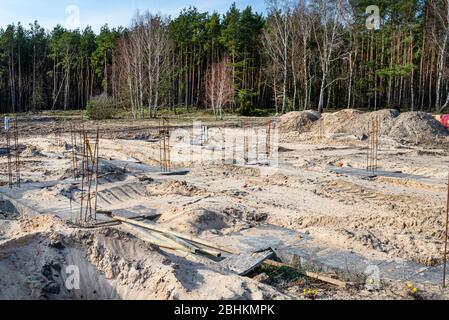 Verstärkungsstäbe ragen aus dem Boden an einem Ort, wo es Betonpfosten, der Anfang des Hauses Rohre. Stockfoto