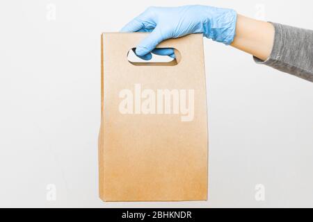 Frauen Hand in Gummihandschuhe halten einen Pappbeutel mit Kopierraum. Konzept der Spendentasche für wohltätige Zwecke Stockfoto