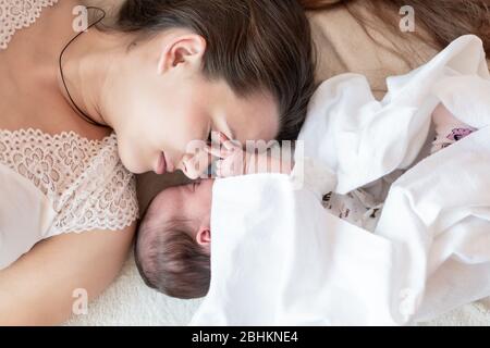 Mutterschaft, Kindheit, Familie, Pflege, Medizin, Schlaf, Gesundheit, Mutterschaft Konzept - Porträt von Mama mit neugeborenem Baby in Windel auf gewickelt