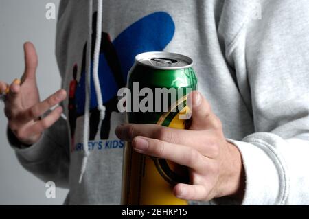 Mann hält eine Bierdose in der einen Hand und einer Zigarette in der anderen Hand. Stockfoto