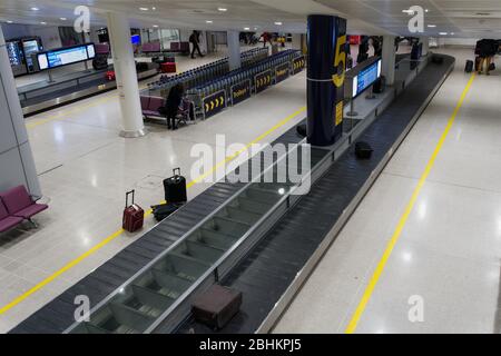 Gepäckausgabe am Flughafen Manchester, Großbritannien. Flughafen-Terminal Ankunft leeres Gepäckkarussell mit geparkten Trolleys im Hintergrund. Stockfoto