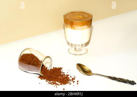 Tasse eisgekühlter Dalgona Kaffee, modischer flauschiger cremiger Schlagkaffee auf einem trendigen farbigen Hintergrund. Stockfoto
