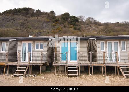 Hölzerne Sommerferien Chalets stehen auf Stelzen am Rande des Monmouth Beach, Lyme Regis, Südengland. Stockfoto