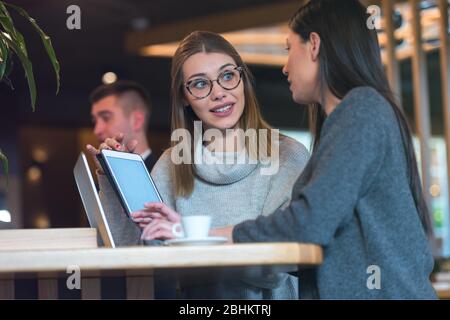 Zwei junge Geschäftsfrauen sprechen in einer Café-Bar bei Caffe Brems über neue Projekte. Stockfoto