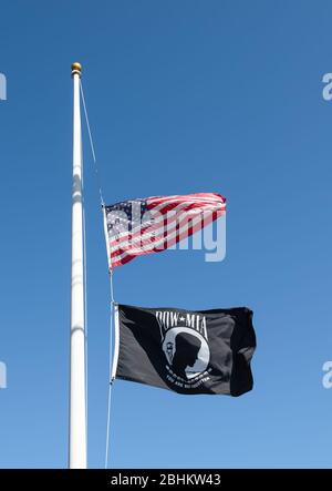 Kriegsgefangener MIA und amerikanische Flagge, beide auf demselben Fahnenmast am Halbmast. Stockfoto