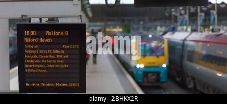 Infopoard für die Zugabfahrt am Bahnhof Manchester Piccadilly mit einem Zug im Hintergrund Stockfoto