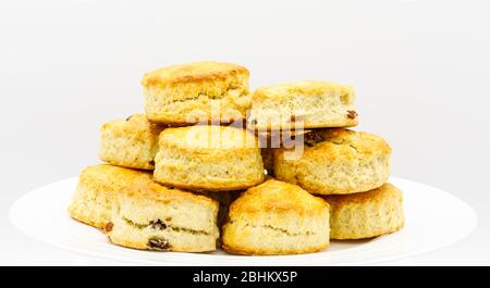Stapel von goldenen frisch gebackenen gemischten Ebene und Obst Scones auf einem weißen Teller präsentiert, für einen Cream Tea vorbereitet: Nahaufnahme Stockfoto