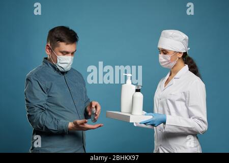 Arzt Anwendung antibakteriellen Spray auf Patienten Hände auf blauem Hintergrund Stockfoto