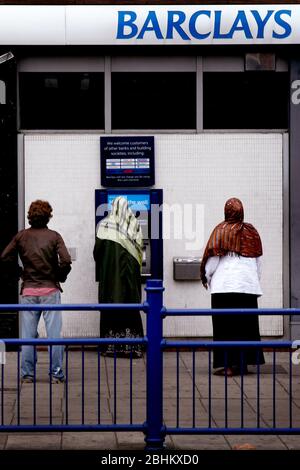 Verschleierte Frauen mit einem Barclays-Geldautomaten Stockfoto