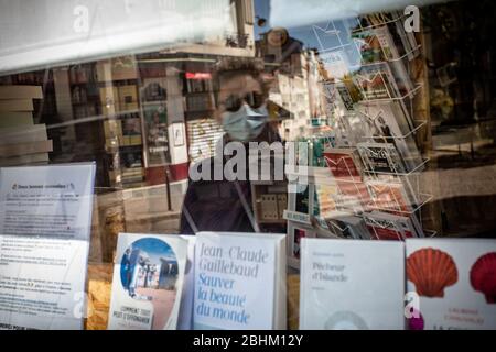 Paris, Frankreich. April 2020. Ein Mann mit einer Gesichtsmaske spiegelt sich am 26. April 2020 in einem Fenster einer Buchhandlung in Paris, Frankreich, wider. In Frankreich stieg die Zahl der COVID-19-Todesfälle am Sonntag um 242 auf 22,856, die niedrigste tägliche Zunahme dieser Woche, was dem Gesundheitssystem des Landes, das die Sperrung am 11. Mai aufheben will, Erleichterung bringt, wie Daten des Gesundheitsministeriums zeigen. Kredit: Aurelien Morissard/Xinhua/Alamy Live News Stockfoto