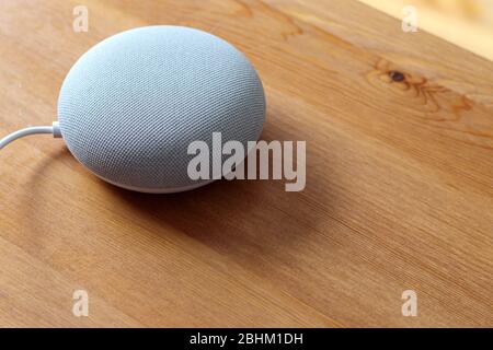 Ein Google Nest Mini Smart Lautsprecher sitzt auf einem Holztisch Stockfoto