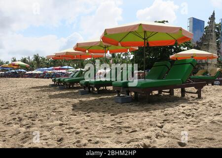 Liegestühle und Liegen und Sonnenschirme für Schatten am Strand von Kuta Bali Stockfoto