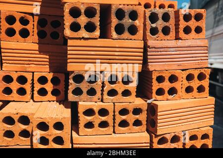 Hohle rote Ziegel in einem Stapel gestapelt, bereit für den Einsatz im Bau oder zum Verkauf. Baumaterial. Ordentlich gefaltet Ziegel, Foto für die Werbung. Kopieren Stockfoto