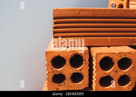 Hohle rote Ziegel in einem Stapel gestapelt, bereit für den Einsatz im Bau oder zum Verkauf. Baumaterial. Ordentlich gefaltet Ziegel, Foto für die Werbung. Kopieren Stockfoto