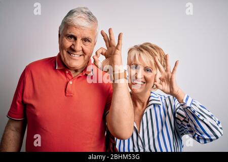 Senior schönes Paar zusammen stehend über isolierten weißen Hintergrund lächelnd positiv tun ok Zeichen mit Hand und Finger. Erfolgreicher Ausdruck. Stockfoto