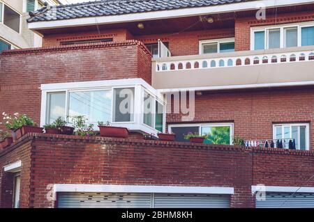 Busan, Südkorea, 13. September 2019: Nahaufnahme der Ziegelhausfassade mit Blumentöpfen und Waschküche Stockfoto